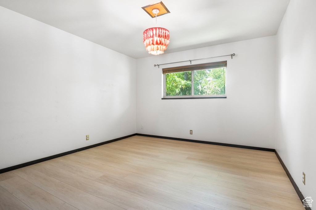 Unfurnished room with light wood-type flooring and a notable chandelier