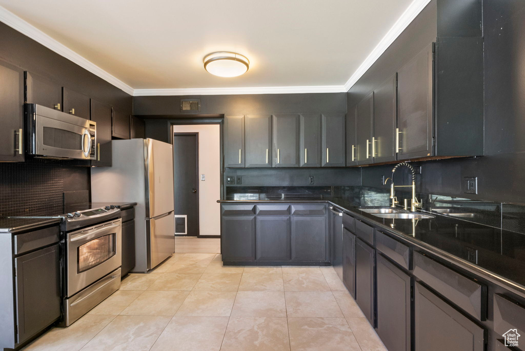 Kitchen with stainless steel appliances, decorative backsplash, crown molding, sink, and light tile patterned floors