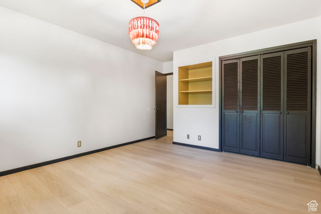 Unfurnished bedroom featuring light hardwood / wood-style floors, a closet, and a chandelier