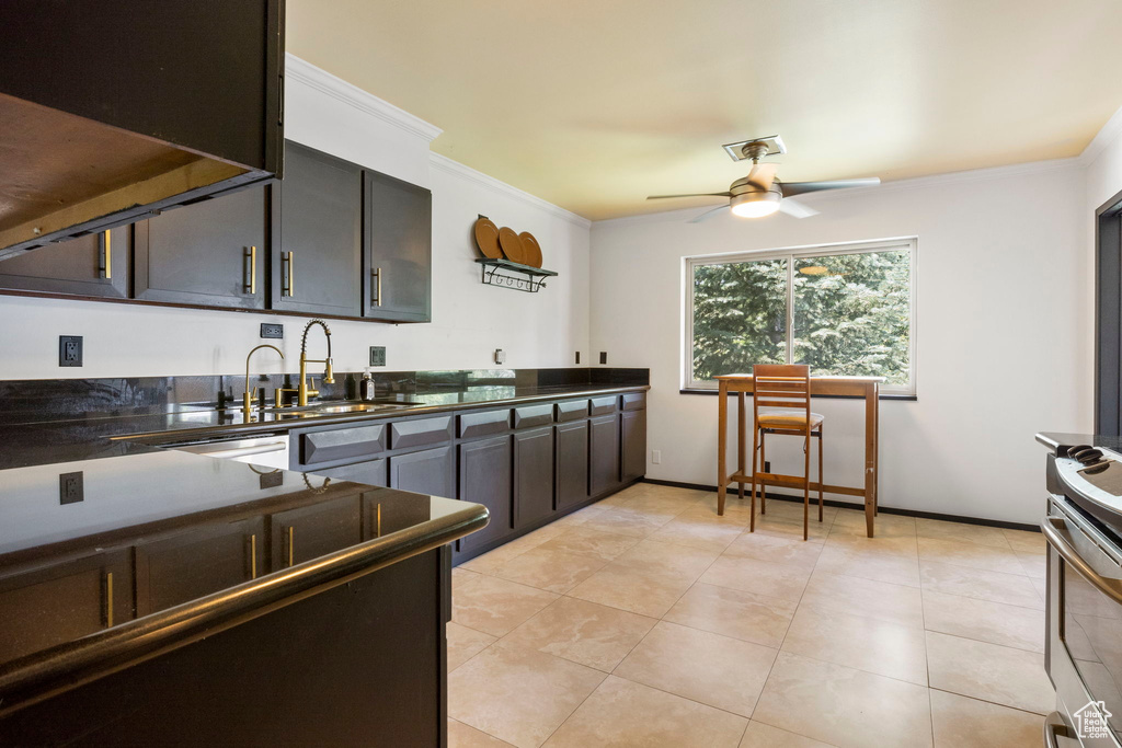 Kitchen with sink, light tile patterned flooring, ceiling fan, and stove