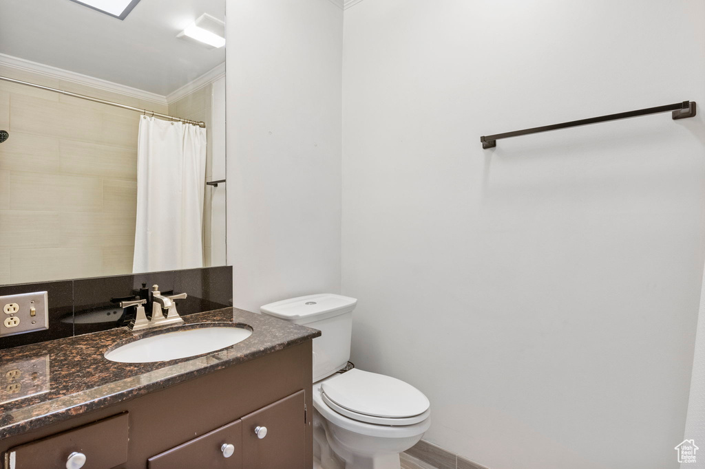 Bathroom with vanity, crown molding, and toilet