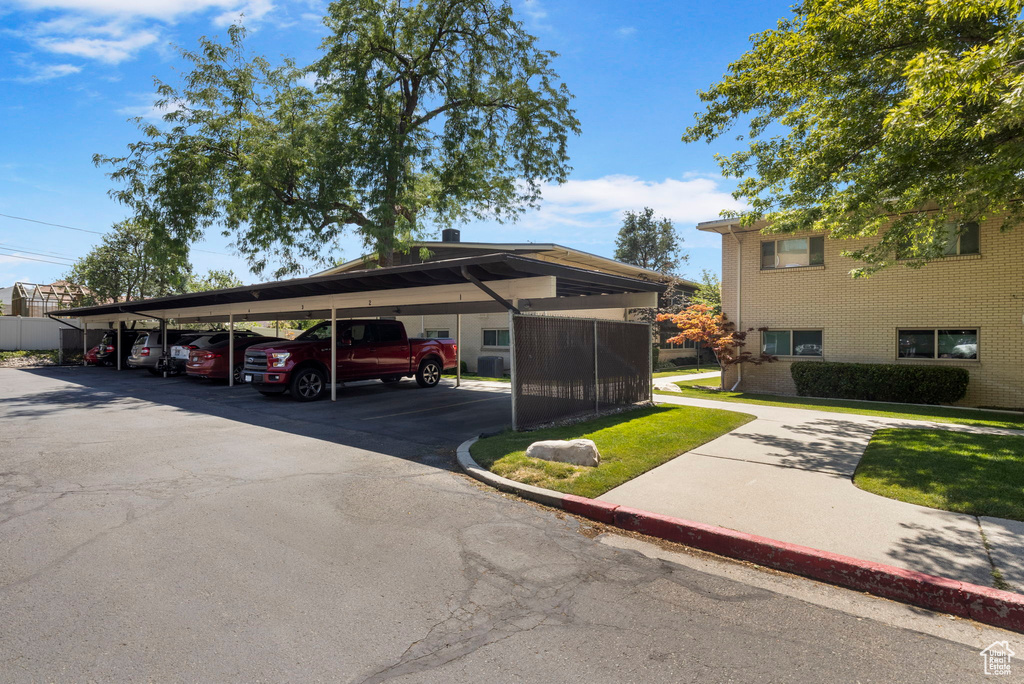 View of parking / parking lot with a lawn and a carport