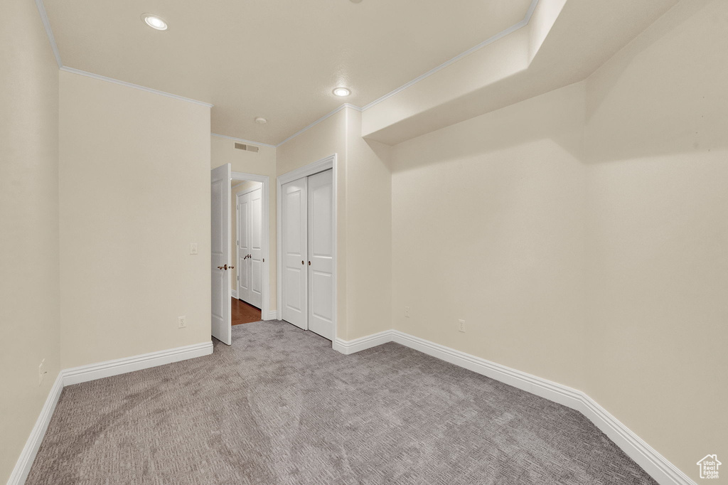 Unfurnished bedroom with a closet, ornamental molding, and carpet