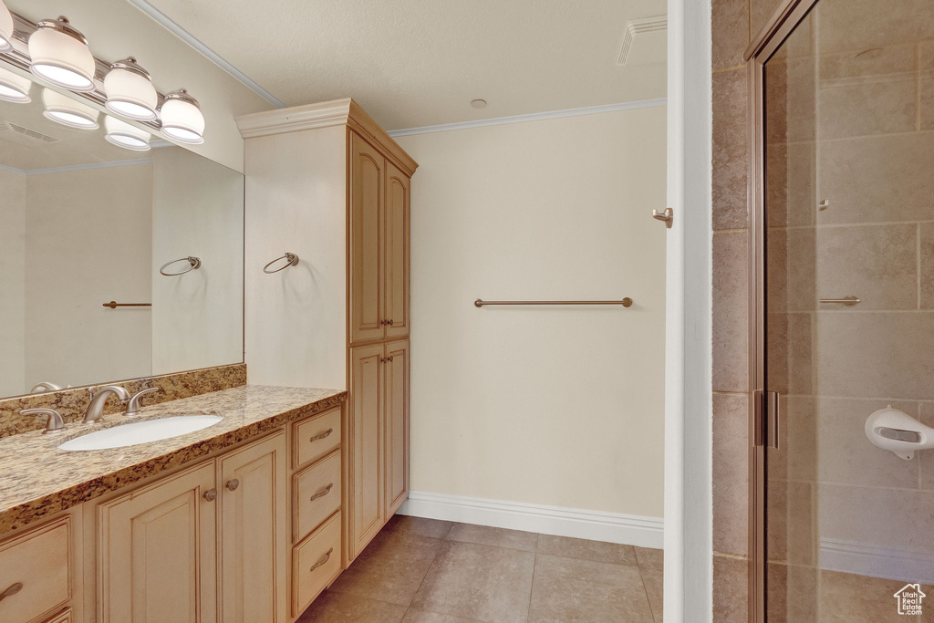 Bathroom with a shower with shower door, tile patterned floors, vanity, and ornamental molding