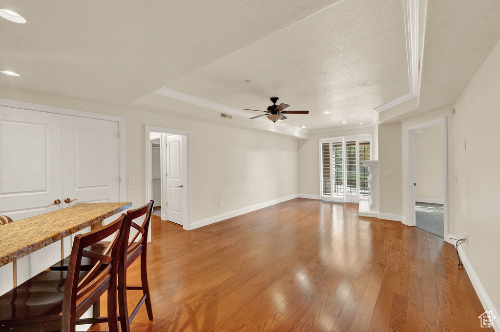 Unfurnished living room featuring ceiling fan, hardwood / wood-style flooring, and a tray ceiling