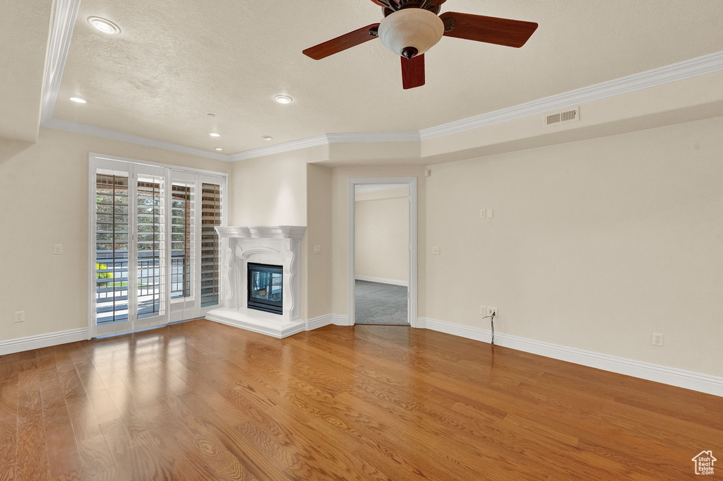 Unfurnished living room featuring ornamental molding, hardwood / wood-style floors, and ceiling fan