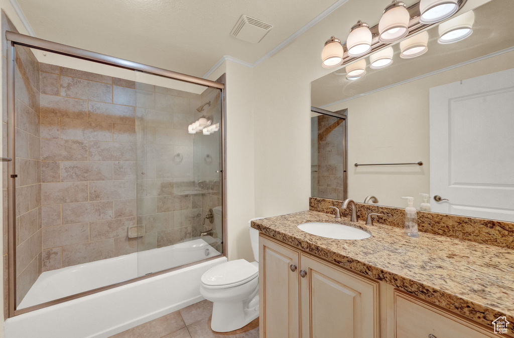 Full bathroom featuring vanity, ornamental molding, enclosed tub / shower combo, toilet, and tile patterned flooring