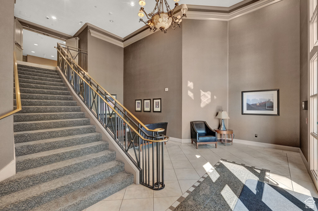 Stairway featuring light tile patterned flooring, an inviting chandelier, and a high ceiling