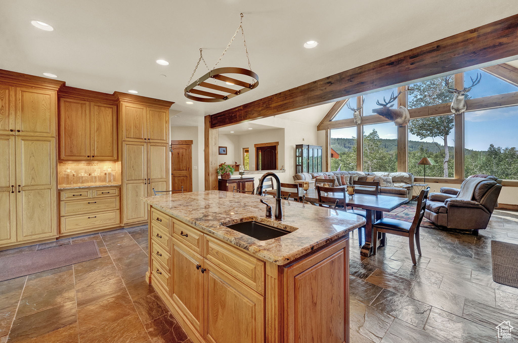 Kitchen with tile patterned floors, sink, a kitchen island with sink, and beam ceiling