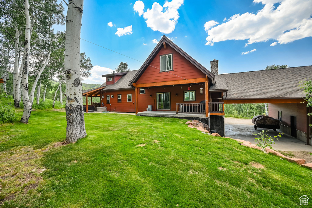 Back of property featuring a porch, a yard, and a carport