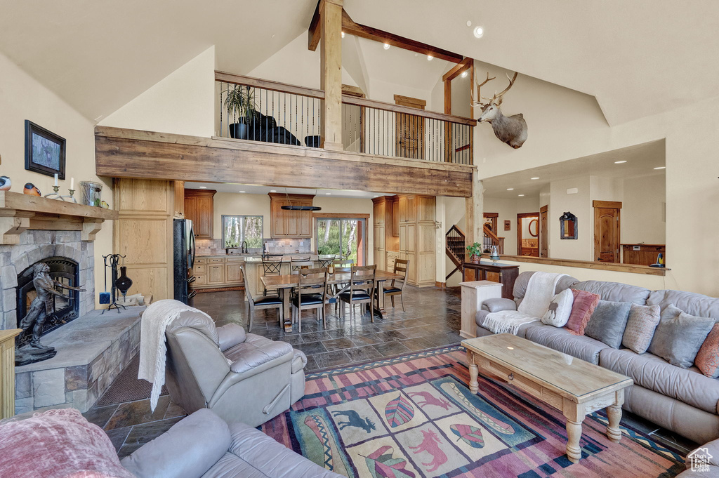 Living room featuring dark tile patterned flooring, a fireplace, and high vaulted ceiling