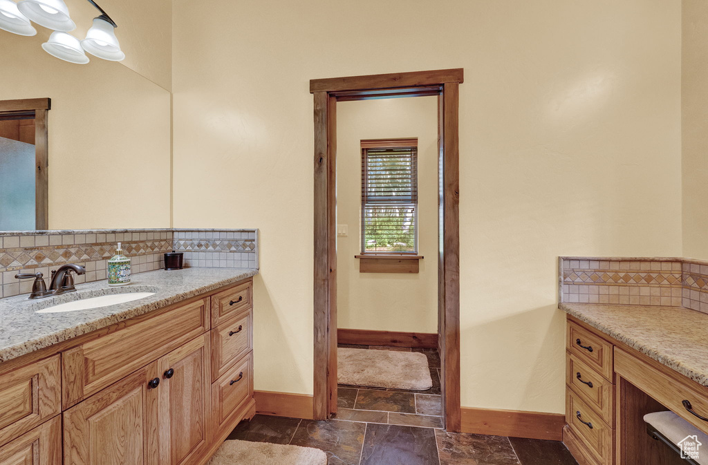 Bathroom with tile patterned floors, tasteful backsplash, and vanity