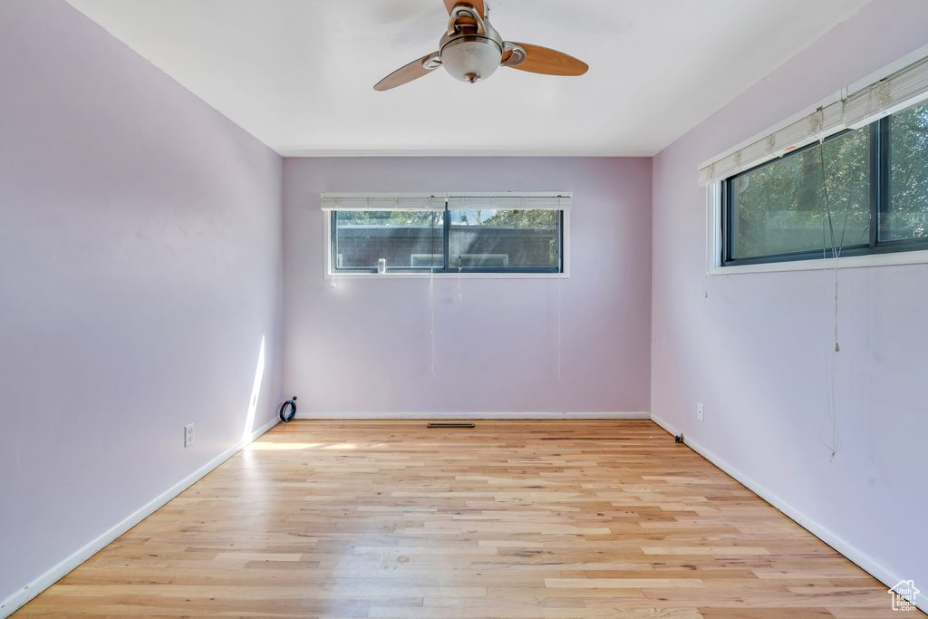 Spare room featuring a wealth of natural light, light wood-type flooring, and ceiling fan