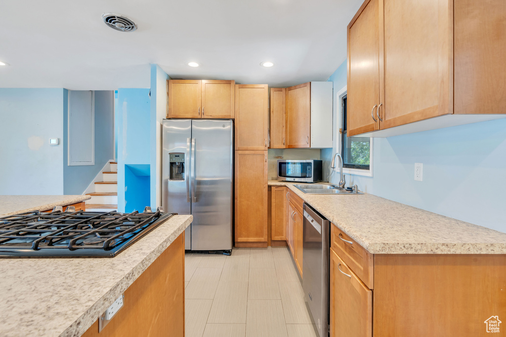 Kitchen with sink, stainless steel appliances, light tile patterned floors, and light brown cabinets