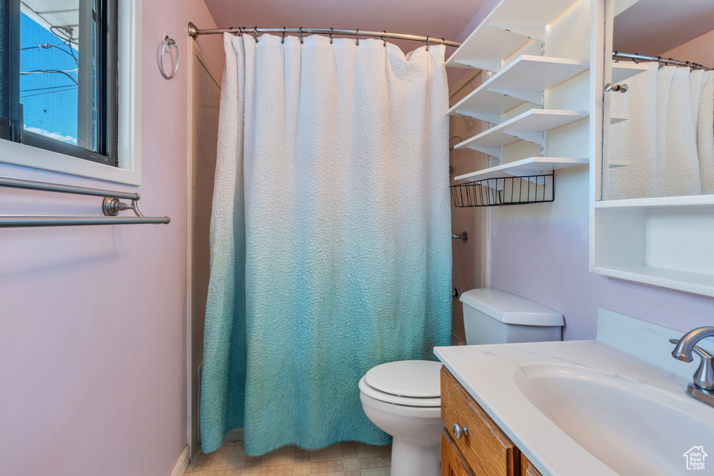 Bathroom featuring tile patterned floors, a shower with shower curtain, vanity, and toilet