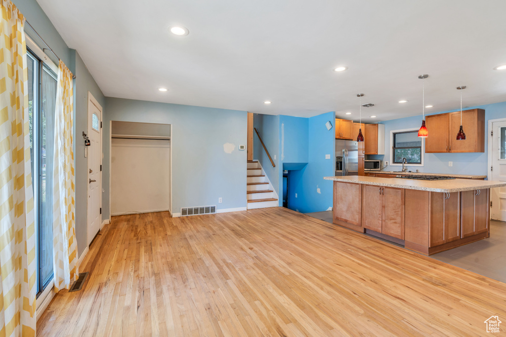 Kitchen featuring sink, appliances with stainless steel finishes, light hardwood / wood-style floors, a kitchen island, and hanging light fixtures