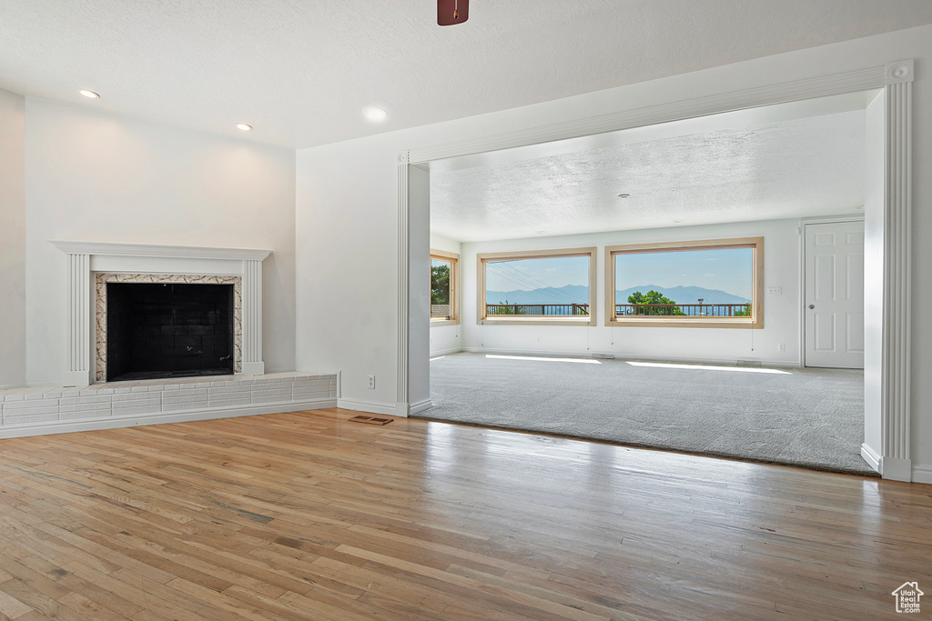 Unfurnished living room with a premium fireplace, carpet floors, and a textured ceiling