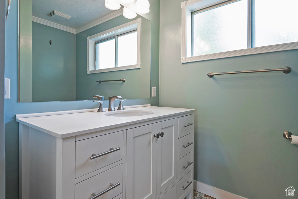 Bathroom with vanity, a textured ceiling, and ornamental molding