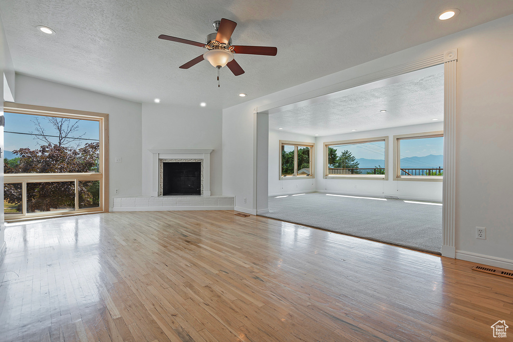 Unfurnished living room with a textured ceiling, light colored carpet, and ceiling fan