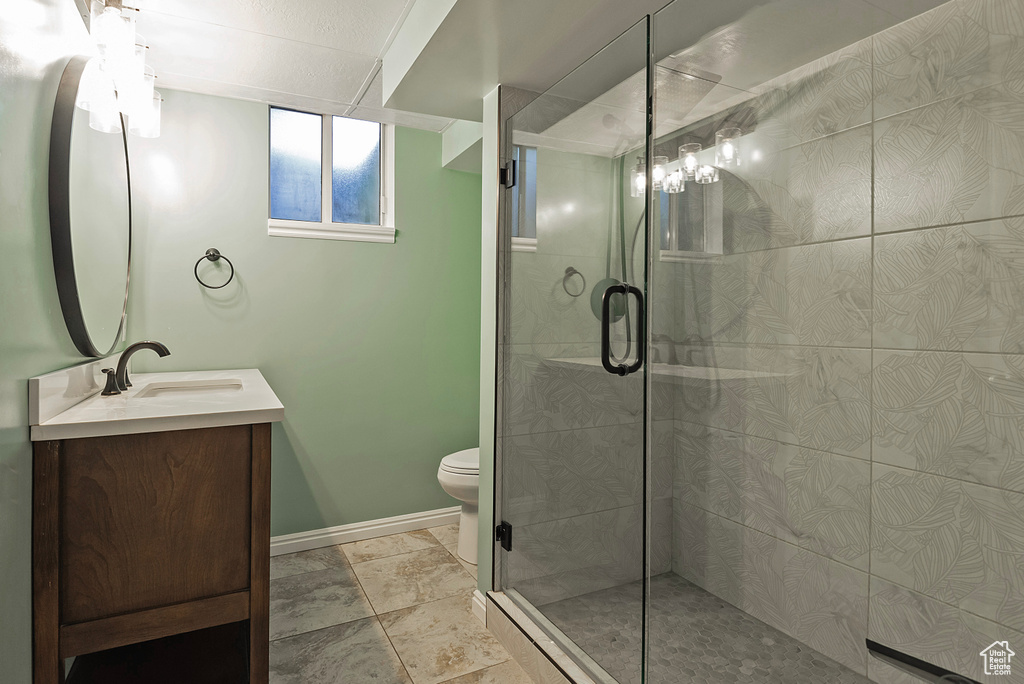 Bathroom with tile patterned floors, toilet, vanity, and an enclosed shower