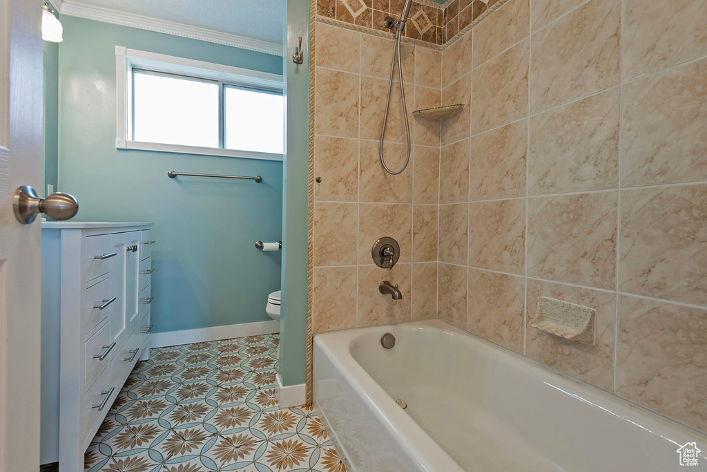 Full bathroom with tile patterned flooring, tiled shower / bath, crown molding, toilet, and vanity