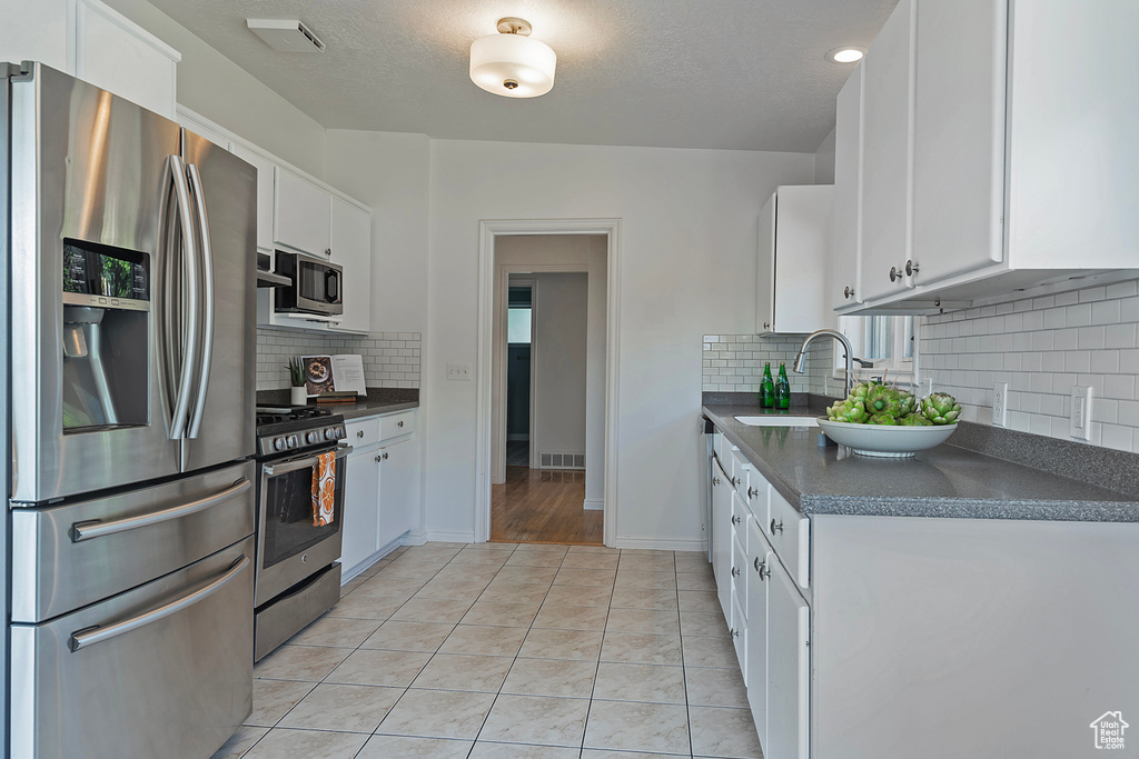 Kitchen with sink, appliances with stainless steel finishes, decorative backsplash, and light hardwood / wood-style floors