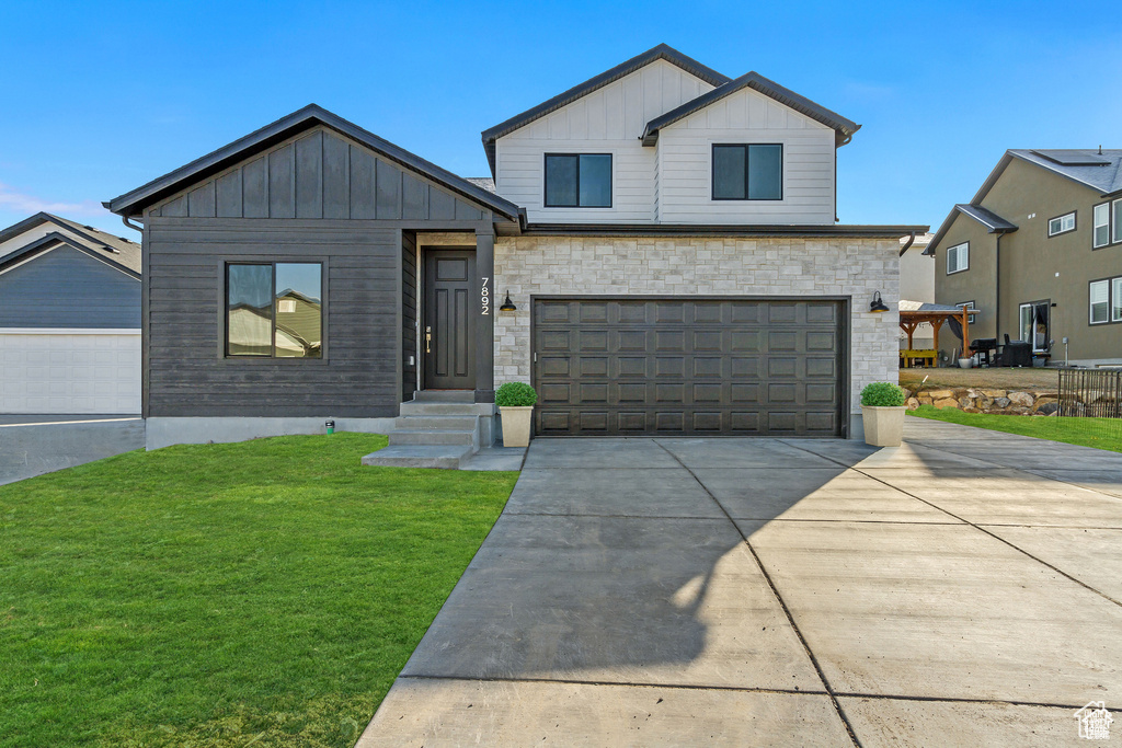 View of front of home with a garage and a front lawn