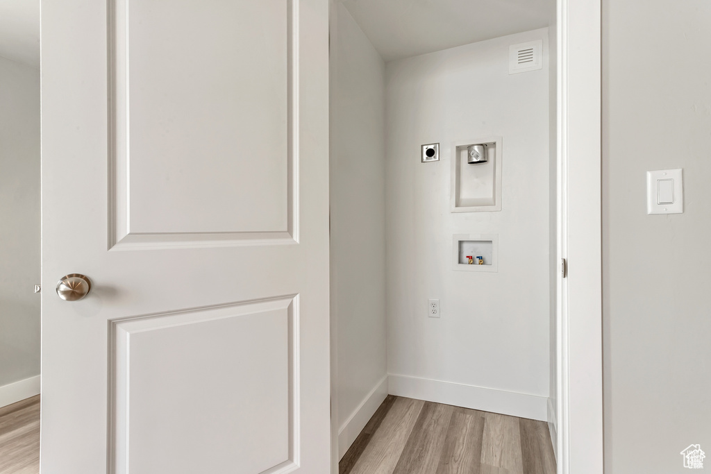 Washroom with light hardwood / wood-style floors, hookup for an electric dryer, and washer hookup