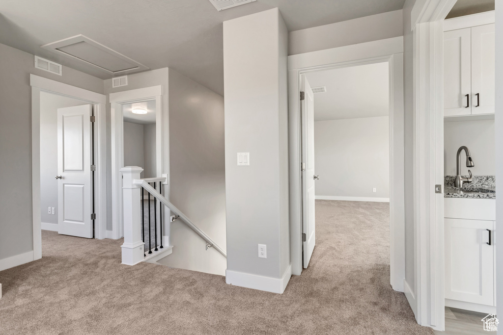 Hallway with sink and light colored carpet