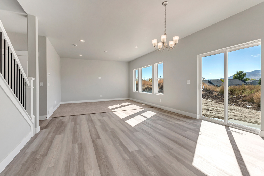 Spare room with a chandelier and light wood-type flooring