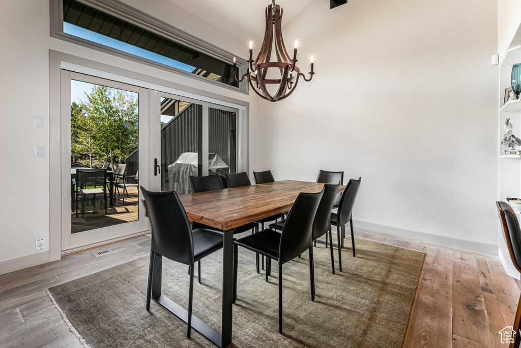 Dining space with lofted ceiling, wood-type flooring, and an inviting chandelier