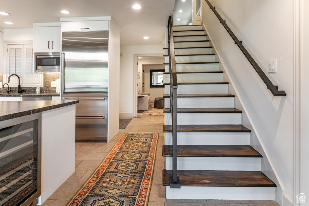 Stairway with light tile patterned flooring, beverage cooler, and sink