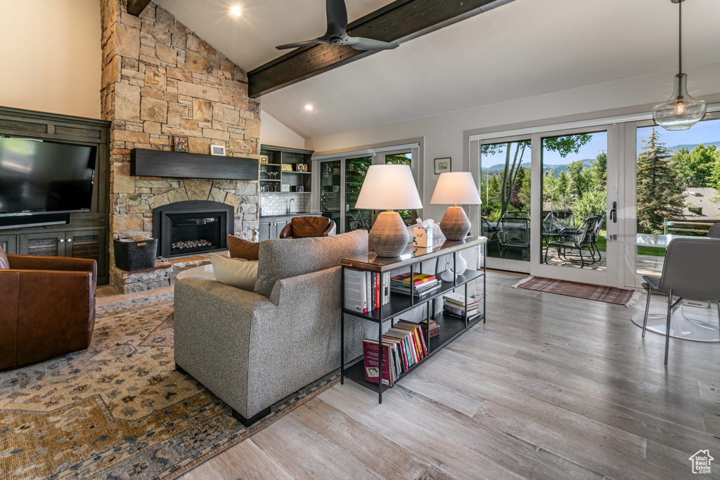 Living room featuring a fireplace, ceiling fan, hardwood / wood-style floors, and beam ceiling