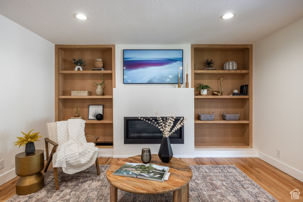 Sitting room with light hardwood / wood-style floors and built in features