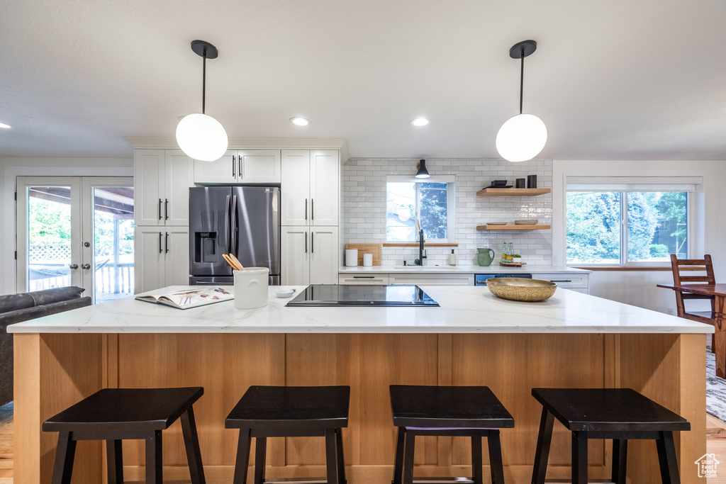 Kitchen featuring white cabinets, stainless steel fridge, sink, and a kitchen island