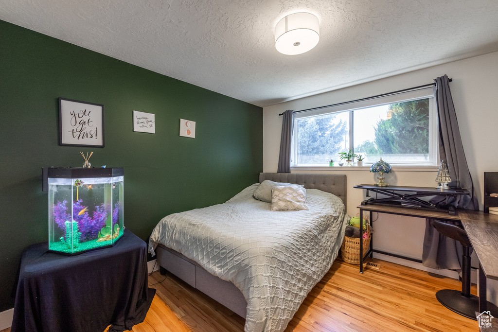 Bedroom with a textured ceiling and light wood-type flooring