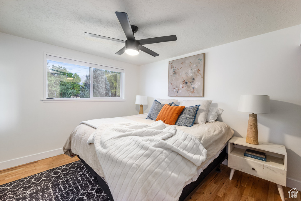 Bedroom with a textured ceiling, hardwood / wood-style floors, and ceiling fan