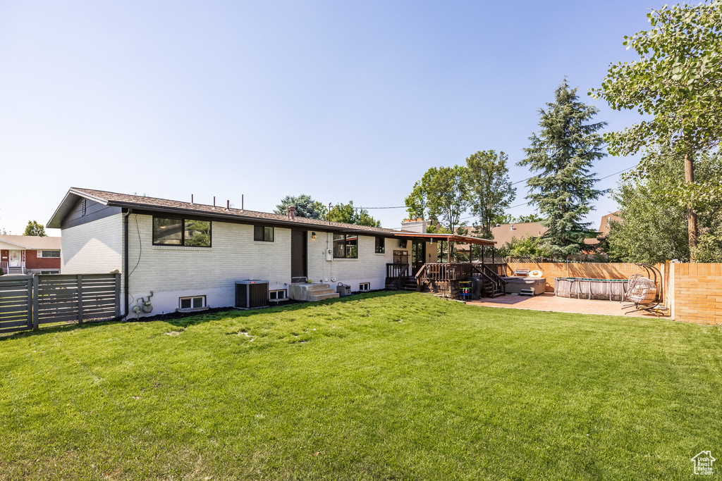 Back of property with a patio, central AC unit, and a yard