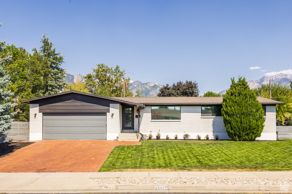 Ranch-style home with a garage, a mountain view, and a front yard