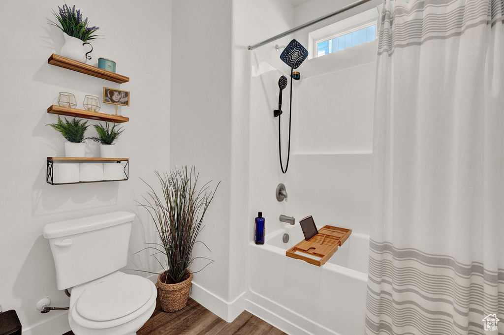 Bathroom featuring toilet, hardwood / wood-style flooring, and shower / bath combination with curtain