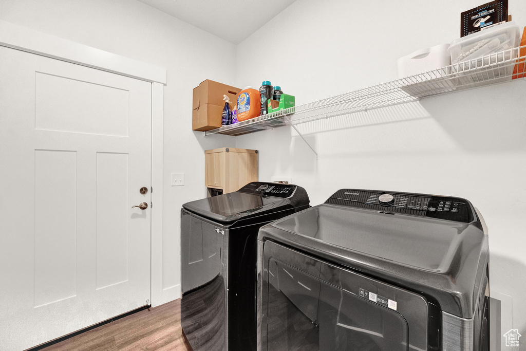 Clothes washing area featuring washing machine and dryer and hardwood / wood-style flooring