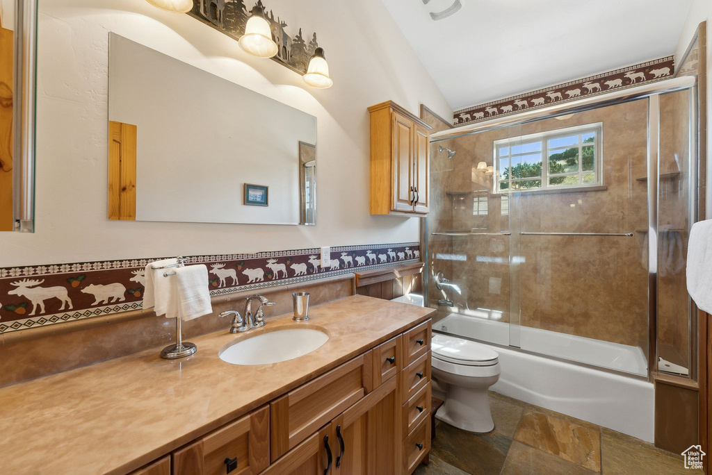 Full bathroom featuring vaulted ceiling, bath / shower combo with glass door, tile patterned floors, toilet, and vanity