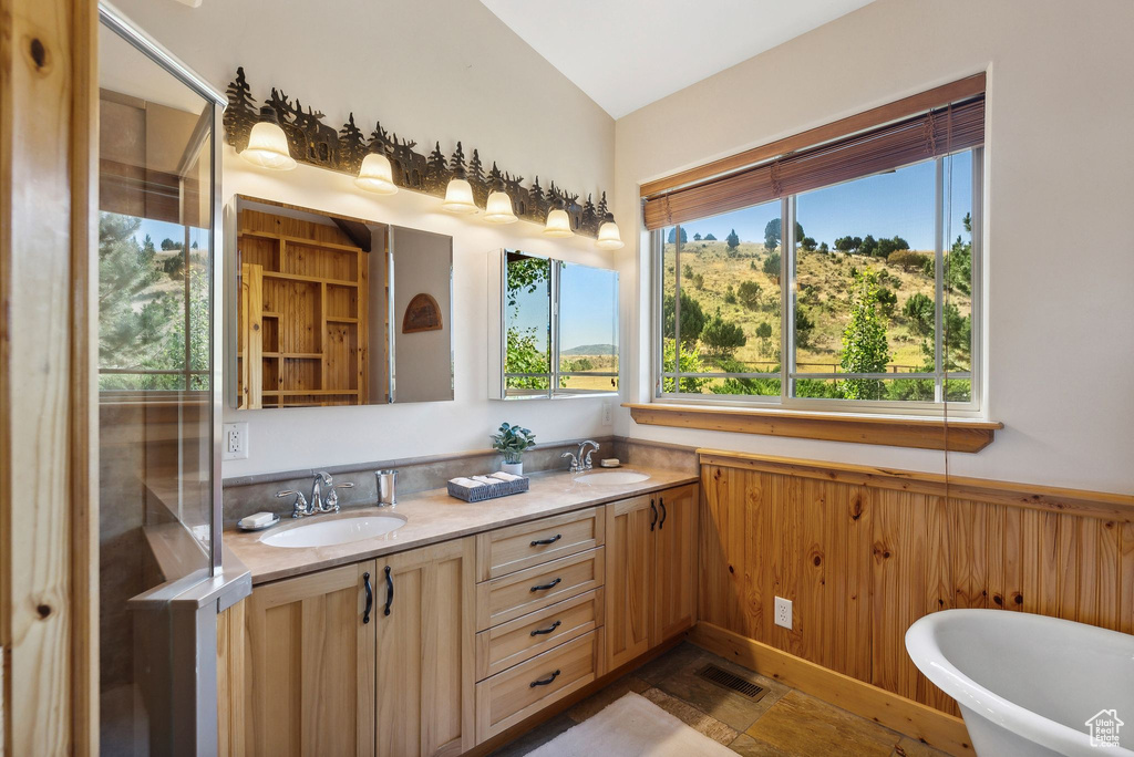 Bathroom featuring lofted ceiling, tile patterned floors, a bathtub, and dual bowl vanity