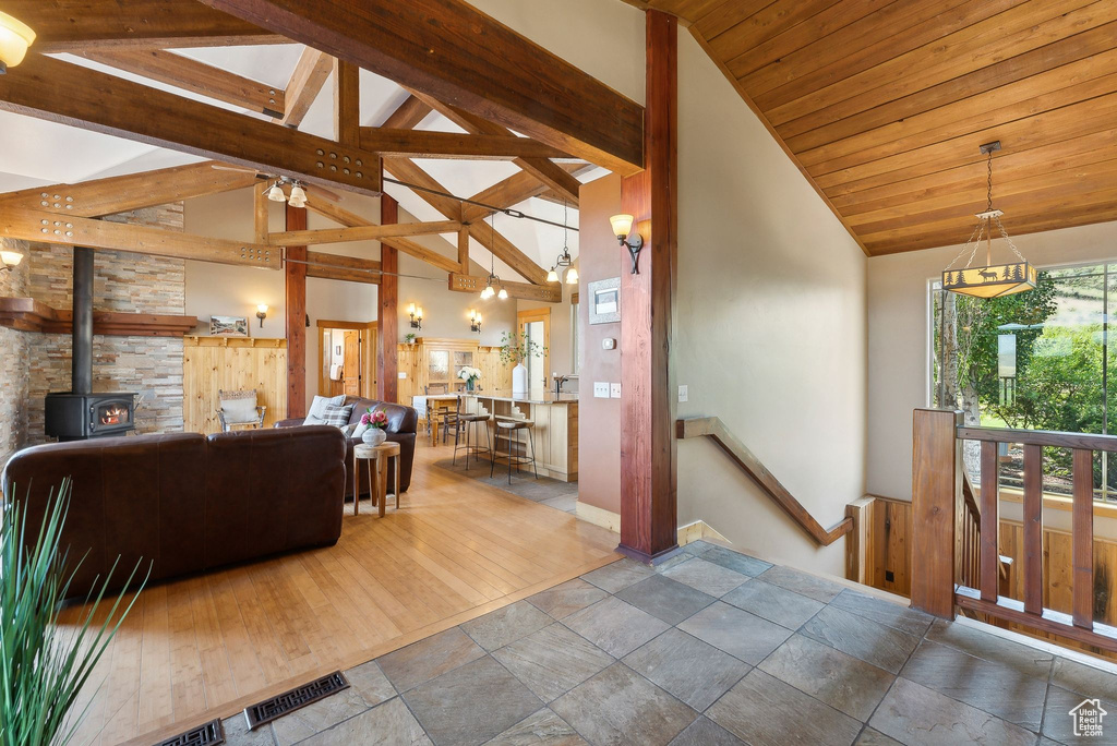 Living room with a wood stove, hardwood / wood-style floors, and high vaulted ceiling