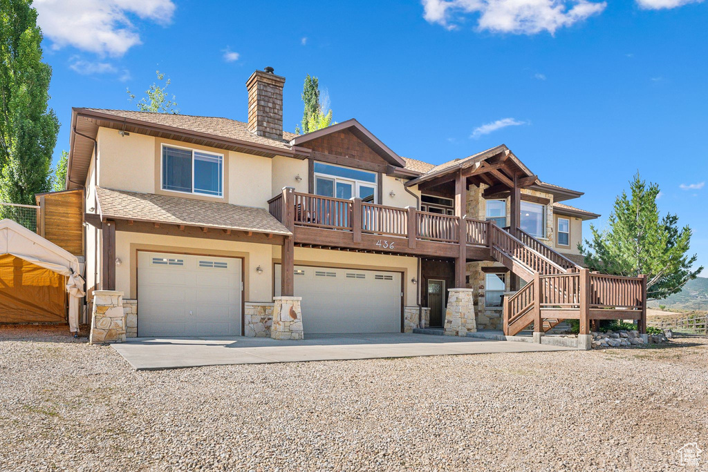 View of front facade featuring a garage and a wooden deck