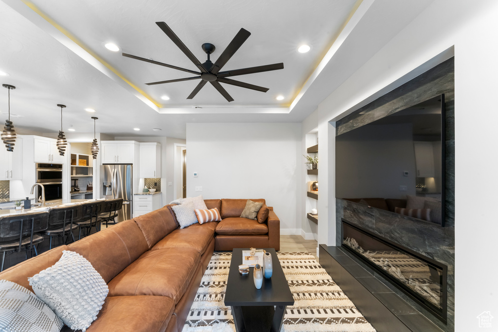 Tiled living room featuring ceiling fan and a tray ceiling