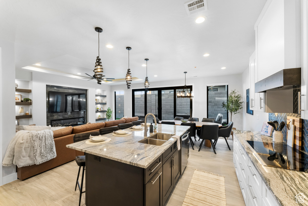 Kitchen featuring ceiling fan, white cabinetry, a breakfast bar area, and dark brown cabinetry