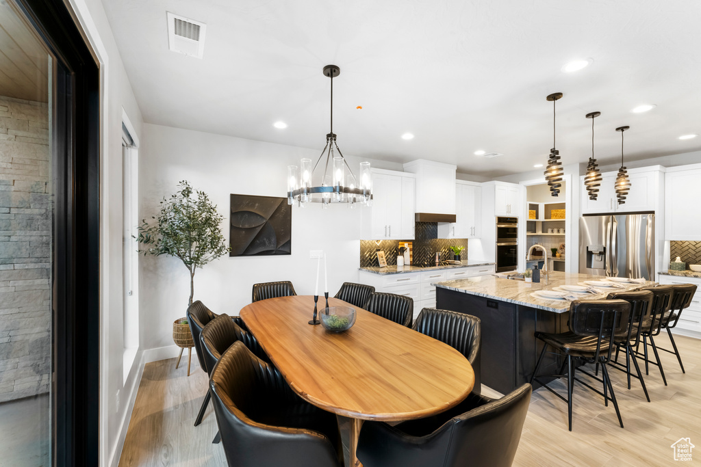 Dining space with a chandelier, sink, and light wood-type flooring