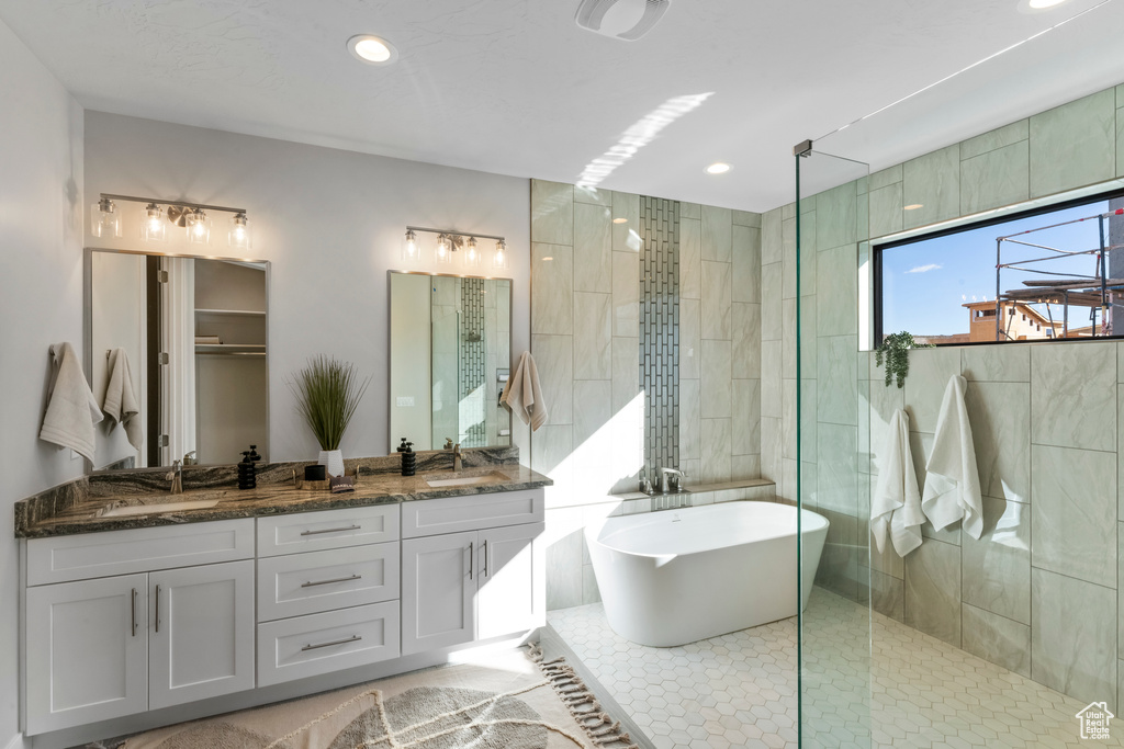 Bathroom with tile patterned flooring, tile walls, separate shower and tub, and dual bowl vanity