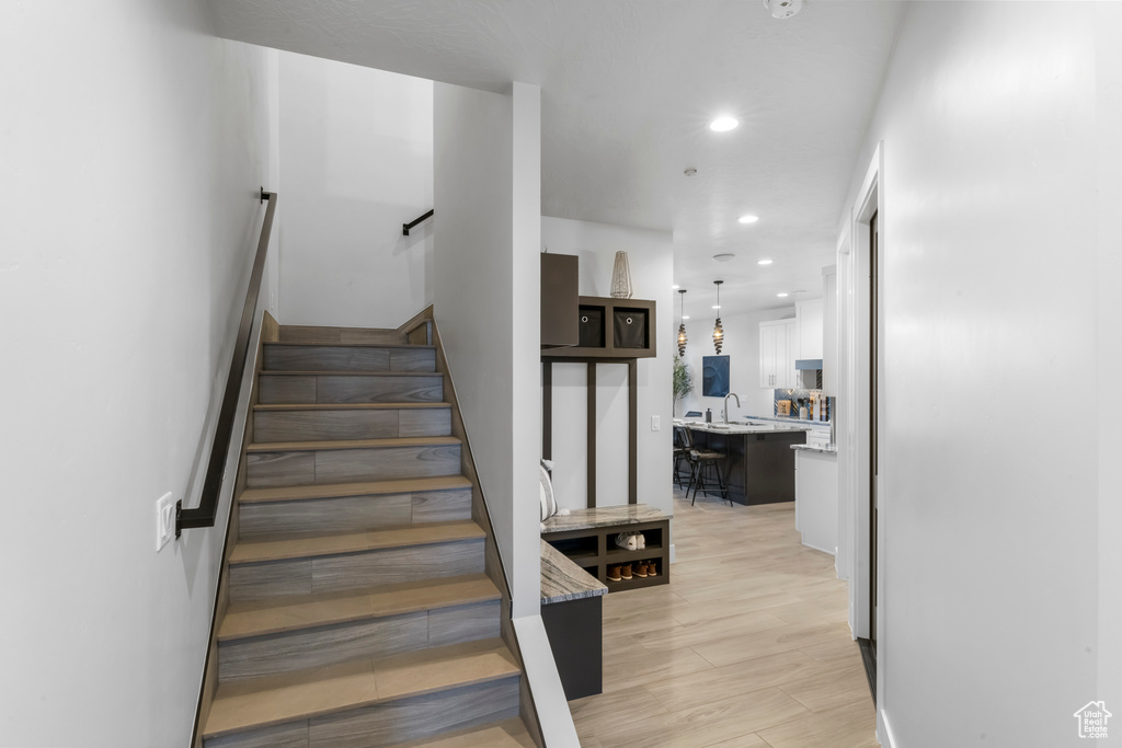 Stairs featuring light hardwood / wood-style floors and sink